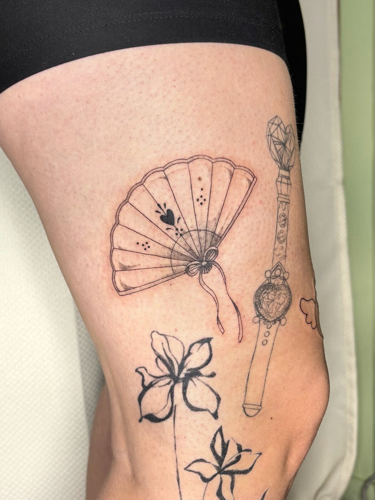 Tatouage art nouveau, éventail et fleurs sur la cuisse